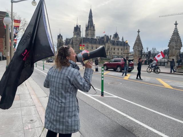 A protester shouts into a megaphone during a protest that broke out after Wellington Street in Ottawa reopened on April 28, 2023. (Falice Chin/CBC - image credit)