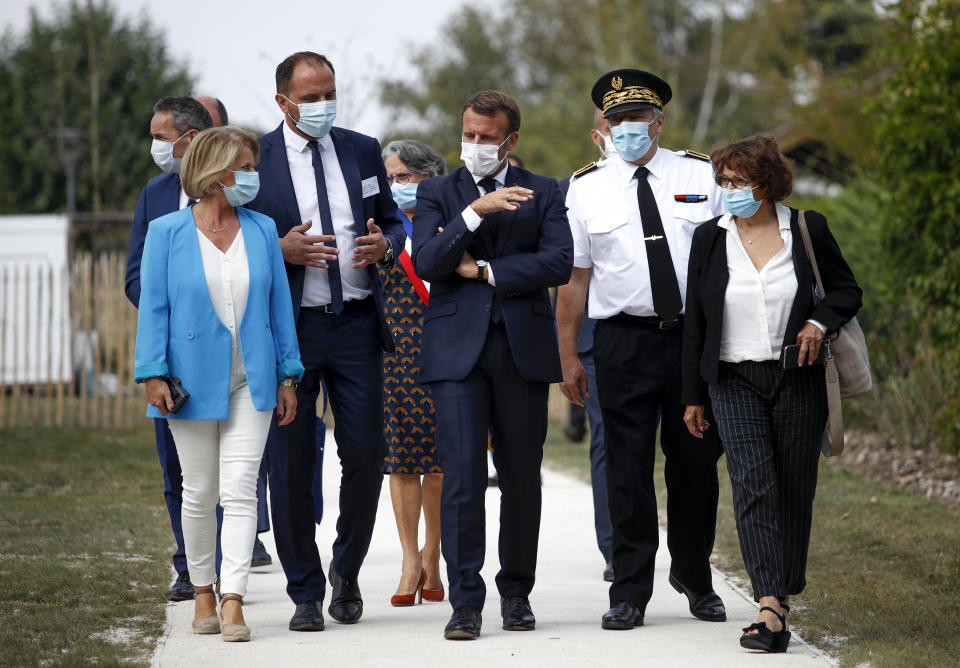 French President Emmanuel Macron, center, and Junior Minister of Autonomy Brigitte Bourguignon, left, talk to officials as they arrive to meet healthcare workers and residents at the 'La Bonne Eure' nursing home in Bracieux, central France, Tuesday, Sept. 22, 2020. For the first time in months, virus infections and deaths in French nursing homes are on the rise again. (Yoan Valat/Pool Photo via AP)