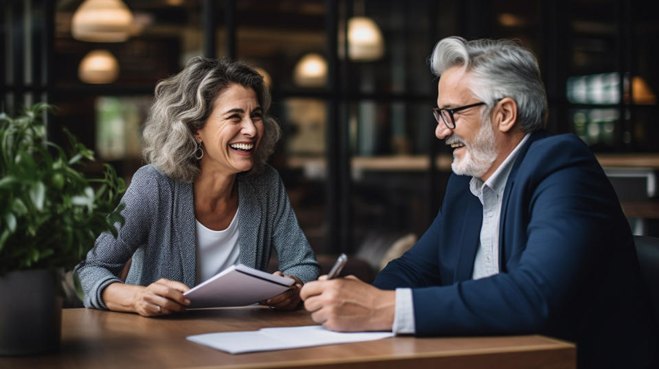 An elderly customer discussing her retirement options with a smiling life insurance agent.