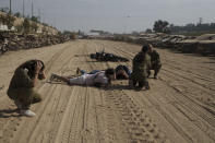 Israeli soldiers and journalists take cover as a siren warns of incoming rockets fired from the Gaza Strip in an area where hundreds of destroyed vehicles are kept that were damaged in the bloody Oct. 7 cross-border attack by Hamas militants, in which at least 1,200 people were killed and 240 others were taken hostage, outside the town of Netivot, southern Israel, Sunday, Nov. 5, 2023. (AP Photo/Leo Correa)