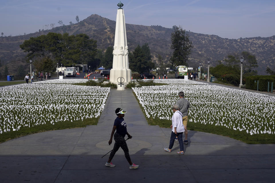 FILE - Visitors walk around a memorial for victims of COVID-19 at the Griffith Observatory, Nov. 19, 2021, in Los Angeles. The U.S. death toll from COVID-19 topped 800,000, a once-unimaginable figure seen as doubly tragic, given that more than 200,000 of those lives were lost after the vaccine became available practically for the asking. (AP Photo/Marcio Jose Sanchez, File)