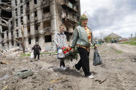 FILE - Women walk past a destroyed apartment building in Mariupol, in territory under the government of the Donetsk People's Republic, eastern Ukraine, Monday, May 2, 2022. (AP Photo/Alexei Alexandrov, File)