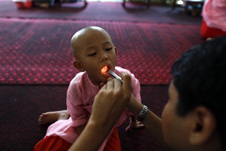 Doctor Ye Thiha Htwe (L) examines a Buddhist novice nun in the Healthy Farm charity clinic at a monastery outside Yangon November 2, 2013. REUTERS/Soe Zeya Tun