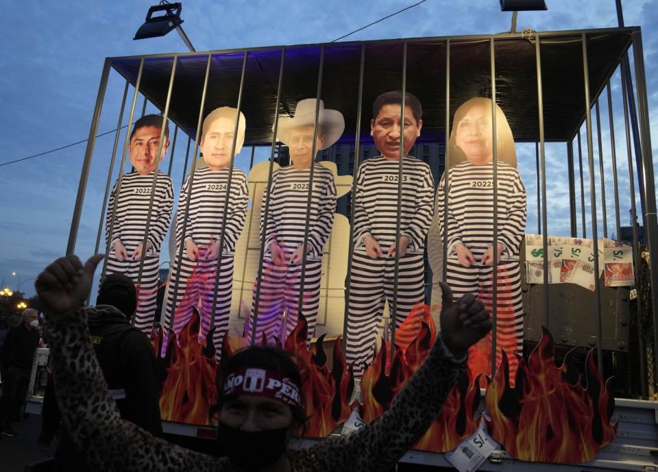 Faux flames burn at the base of a mock prison cell holding several cutout figures in black-and-white striped prison outfits.