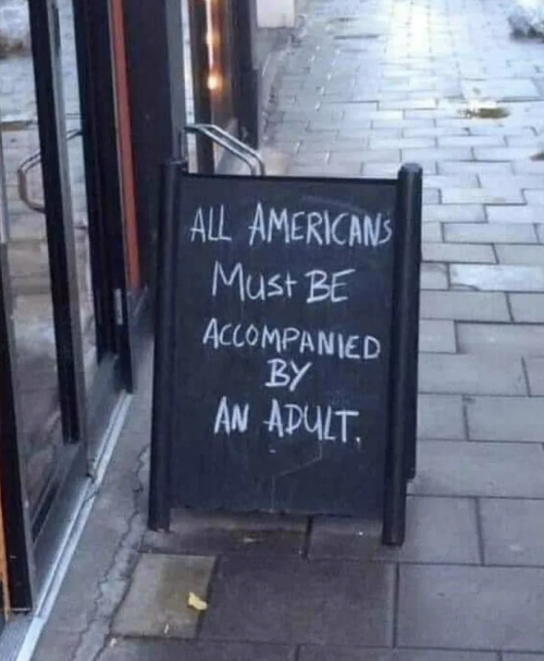 Sign outside a venue humorously states "ALL AMERICANS Must BE ACCOMPANIED BY AN ADULT."