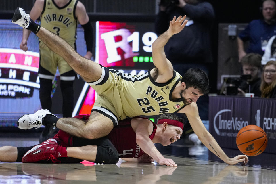 Purdue guard Ethan Morton (25) and Rutgers guard Paul Mulcahy (4) dive for a loose ball during the first half of an NCAA college basketball game in West Lafayette, Ind., Monday, Jan. 2, 2023. (AP Photo/Michael Conroy)