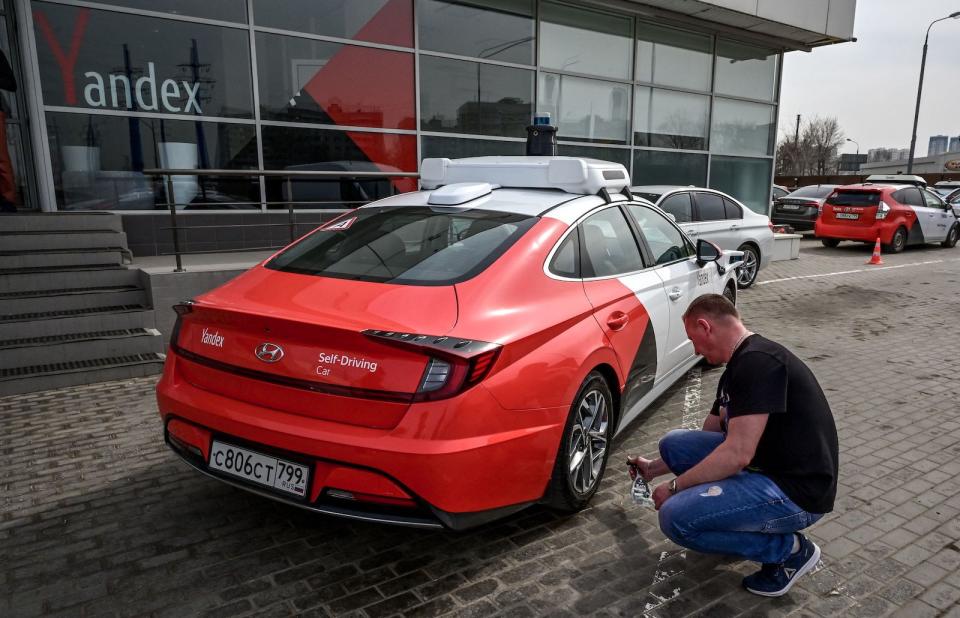 A picture taken on April 15, 2021 shows an engineer cleaning the wheel of a self-driving car, developed by Russian internet giant Yandex, at the company's parking lot in Moscow. (Photo by Yuri KADOBNOV / AFP) (Photo by YURI KADOBNOV/AFP via Getty Images)