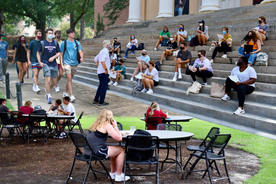 From top left: Students walking around Russell House, University of South Carolina’s student union; A professor holds class outside on the steps of Longstreet Theatre on USC’s campus; USC put tables and chairs on the grass around the student union so there is more seating area because indoor capacity is limited. Students are expected to wipe down these tables and chairs themselves upon use