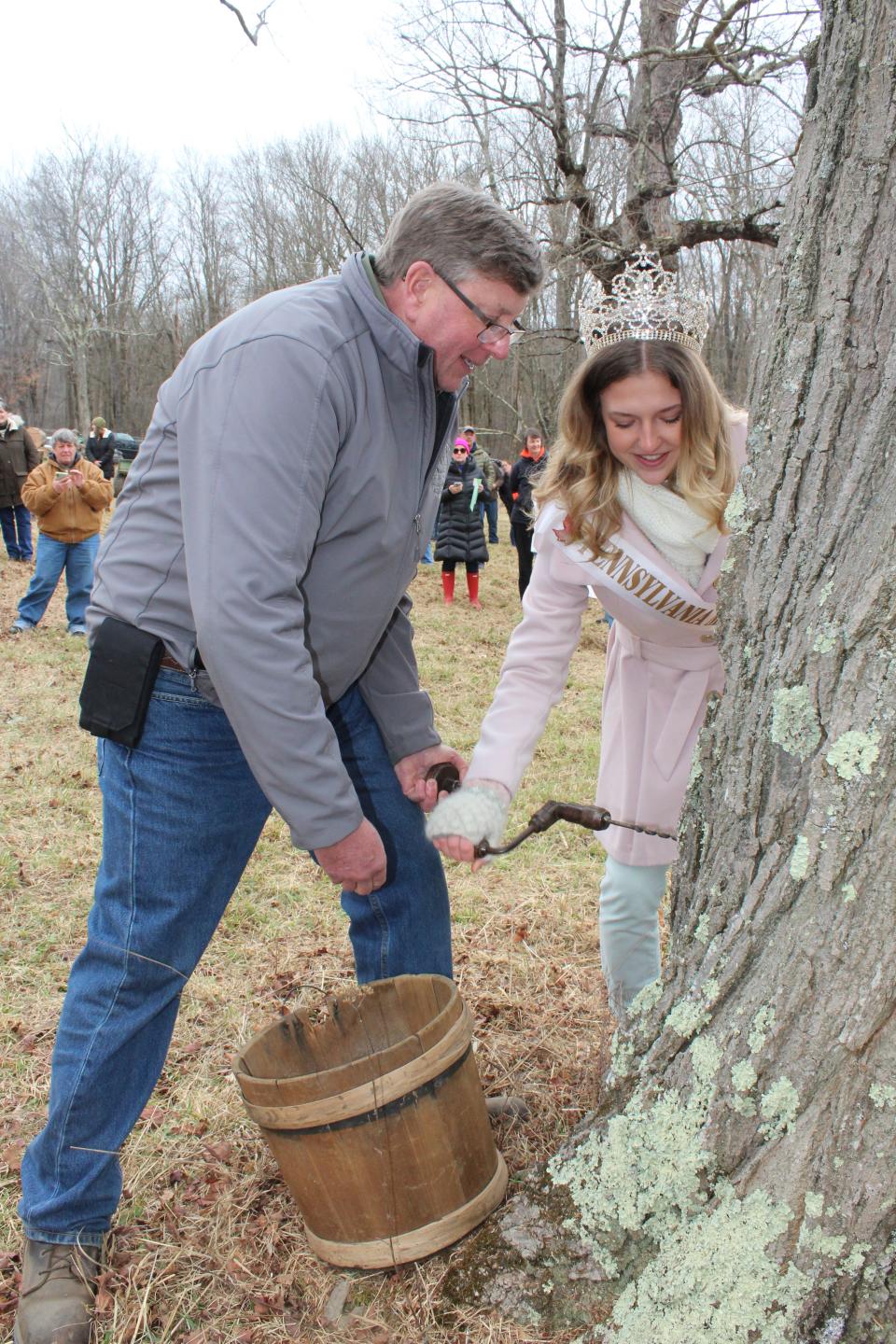 Reigning royalty 2022 Maple King Jason Blocher and Queen Maple LXXV Ella Wheeler tap the first official tree for the maple season during the tree tapping ceremony at Sanner Maple Products near Rockwood on Saturday. The sap did start to drip from the old maple tree on the property.