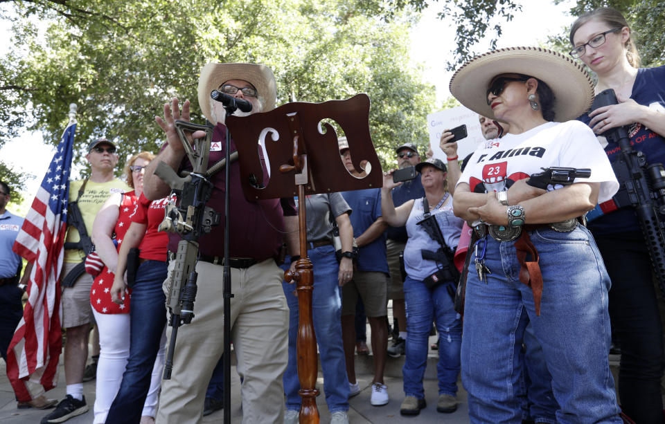 Steven Willeford, holds up a rifle as he and Dr. Alma Arredondo-Lynch, right, holds a pistol as gun rights advocates gather outside the Texas Capitol where Texas Gov. Greg Abbott held a round table discussion, Thursday, Aug. 22, 2019, in Austin, Texas. Abbott is meeting in Austin with officials from Google, Twitter and Facebook as well as officials from the FBI and state lawmakers to discuss ways of combatting extremism in light of the recent mass shooting in El Paso that reportedly targeted Mexicans. (AP Photo/Eric Gay)