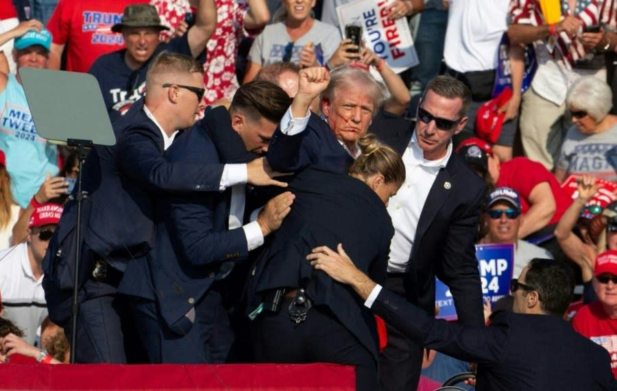 Republican candidate Donald Trump is seen with blood on his face surrounded by secret service agents as he is taken off the stage at a campaign event at Butler Farm Show Inc. in Butler, Pennsylvania, July 13, 2024. Republican candidate Donald Trump was evacuated from the stage at today’s rally after what sounded like shots rang out at the event in Pennsylvania, according to AFP. The former US president was seen with blood on his right ear as he was surrounded by security agents, who hustled him off the stage as he pumped his first to the crowd. Trump was bundled into an SUV and driven away. (Photo by Rebecca DROKE / AFP) (Photo by REBECCA DROKE/AFP via Getty Images)