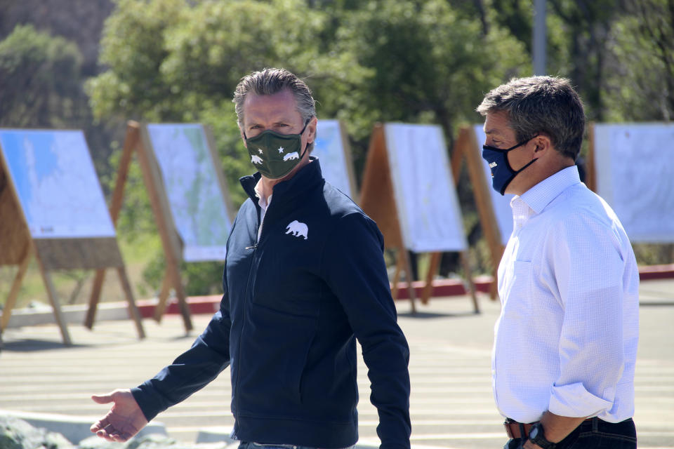 California Gov. Gavin Newsom, left, and California Natural Resources Secretary Wade Crowfoot walk together during a visit to the Loafer Creek State Recreation Area on Tuesday, April 13, 2021, in Oroville, Calif. Newsom signed a law on Tuesday authorizing more than half a billion dollars in new spending to prepare for wildfire season. (AP Photo/Adam Beam)