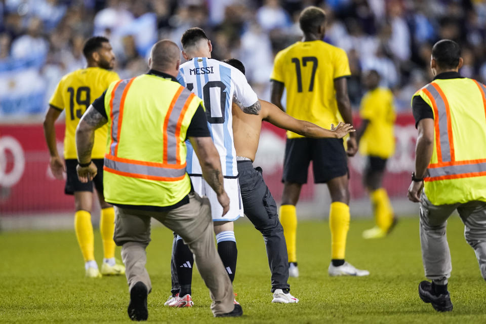 A fan is tackled as he tries to take a selfie with Argentina's player Lionel Messi as he celebrates his goal during the second half of an international friendly soccer match against Jamaica on Tuesday, Sept. 27, 2022, in Harrison, N.J. (AP Photo/Eduardo Munoz Alvarez)