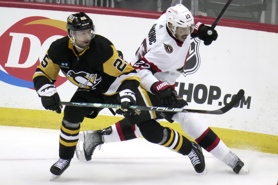 Pittsburgh Penguins' Ryan Poehling (25) and Ottawa Senators' Travis Hamonic (23) battle for puck possession during the first period of an NHL hockey game in Pittsburgh, Monday, March 20, 2023. (AP Photo/Gene J. Puskar)