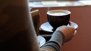 A woman carries a cup of coffee.