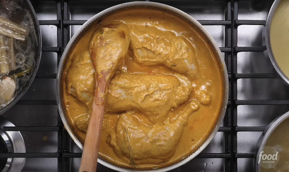 coconut milk mixed in with spices in a pot of chicken