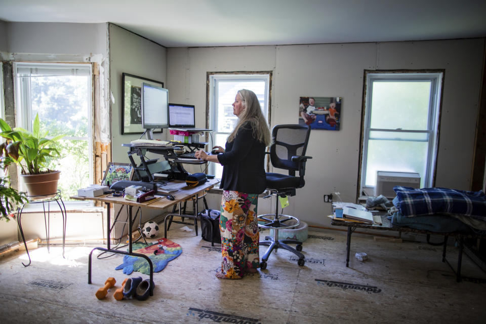 Lisa Edson Neveu, 52, works at the main room of her house in Montpelier, Vt., July 3, 2024 that was damaged by the 2023 flood. A year after catastrophic flooding inundated parts of Vermont, some homeowners are still in the throes of recovery. (AP Photo/ Dmitry Belyakov)