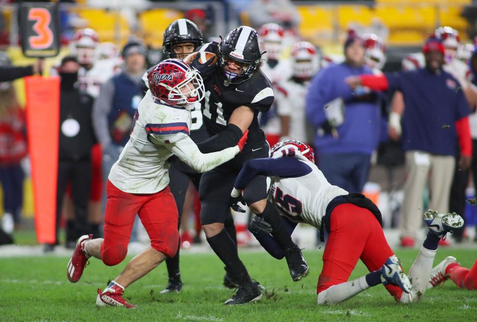 Aliquippa's Cameron Lindsey (11) gets wrapped up by Dominique Cochran (15) and Richard Beermann (4) during the second half of the WPIAL 4A Championship game Friday evening at Acrisure Stadium in Pittsburgh, PA.