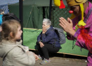 Una mujer se sienta mientras Nimrod Eisenberg, un payaso de la organización Dream Doctors de Israel, entretiene a una niña ucraniana en el cruce fronterizo entre Ucrania y Polonia, en Medyka, sureste de Polonia, el jueves 24 de marzo de 2022. Más de 5 millones de refugiados han huido de Ucrania desde que inició la guerra de Rusia, informó la agencia de refugiados de la ONU el 20 de abril de 2022. Es la mayor crisis de refugiados en Europa desde la Segunda Guerra Mundial. (AP Foto/Sergei Grits, File)
