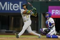 Oakland Athletics' Elvis Andrus (17) follows through on a two-run home run next to Texas Rangers catcher Jonah Heim during the seventh inning of a baseball game in Arlington, Texas, Tuesday, Aug. 16, 2022. (AP Photo/Tony Gutierrez)