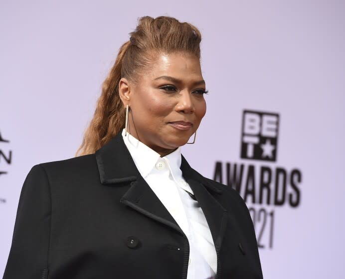 A woman in a white blouse and black blazer-cape