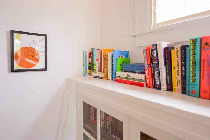 Books on a book shelf on a white dresser.