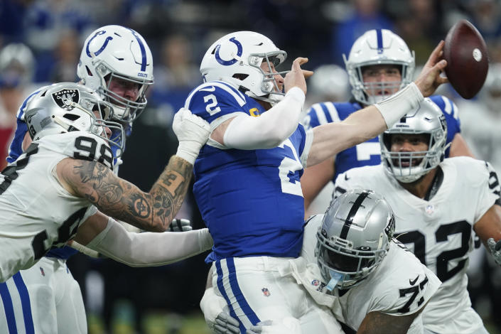 Indianapolis Colts quarterback Carson Wentz (2) passes the ball as he is hit by Las Vegas Raiders defensive end Maxx Crosby (98) and defensive tackle Quinton Jefferson (77) during the first half of an NFL football game, Sunday, Jan. 2, 2022, in Indianapolis. (AP Photo/Darron Cummings)