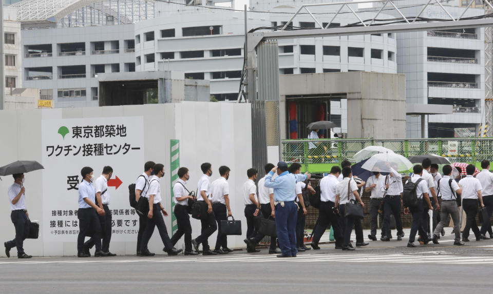 FILE - In this June 16, 2021, file photo, police officers and firefighters arrive to receive the Moderna coronavirus vaccine at a former Tsukiji fish market which was turned to be a temporary mass vaccination center site set up by Tokyo metropolitan government, in Tokyo. After months of delays due to political and bureaucratic bungling as well as a shortage of vaccines, inoculations in Japan are taking off, and the drive is now racing down to the wire with the Olympics starting in one month. (AP Photo/Koji Sasahara, File)