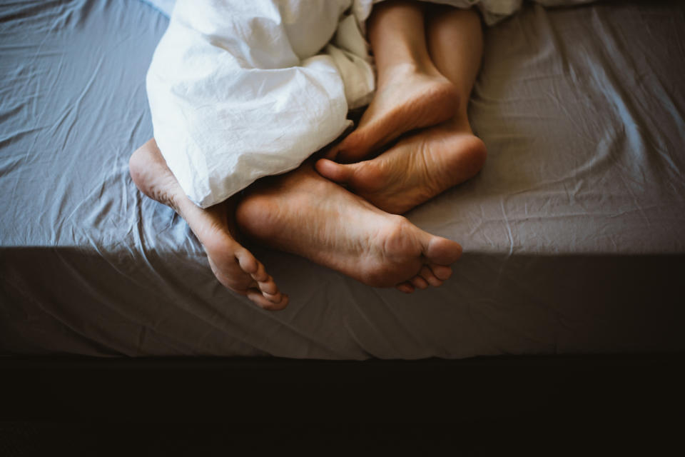 A couple is lying in bed together with their feet tangled up