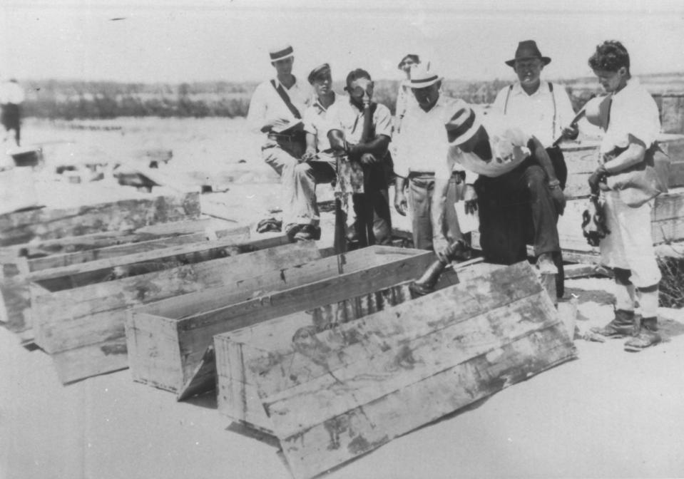 In this undated photo made available by the Keys History & Discovery Center, shows a group of men placing bodies in coffins after the Labor Day hurricane of 1935 in the Florida Keys. Over 400 people, many of them World War I veterans, perished in the storm. They were building bridges to connect the island chain to the mainland when the storm struck. (Keys History & Discovery Center via AP)