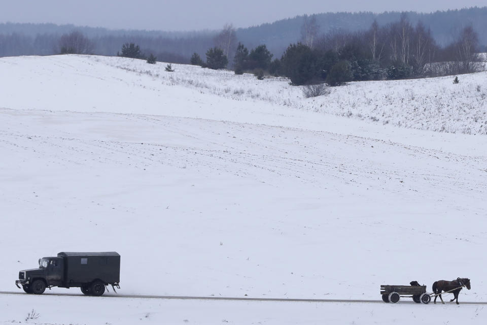 A truck and a traditional cart pass each other in the snow-covered village of Nesutychi, 140 km (87 miles) west of Minsk, Belarus, Saturday, Jan. 12, 2019. Daily temperatures dropped to around -3 Celsius (27 Fahrenheit) in Belarus. (AP Photo/Sergei Grits)