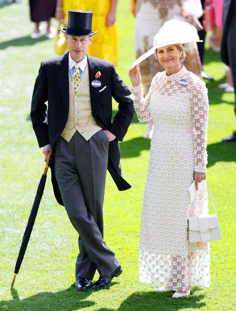 Prince Edward, wearing a morning suit, stands next to his wife Sophie, Duchess of Edinburgh, who is wearing a white dress with floral embellishments.