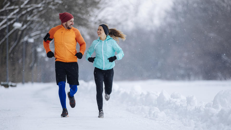 A man and woman run together in the snow
