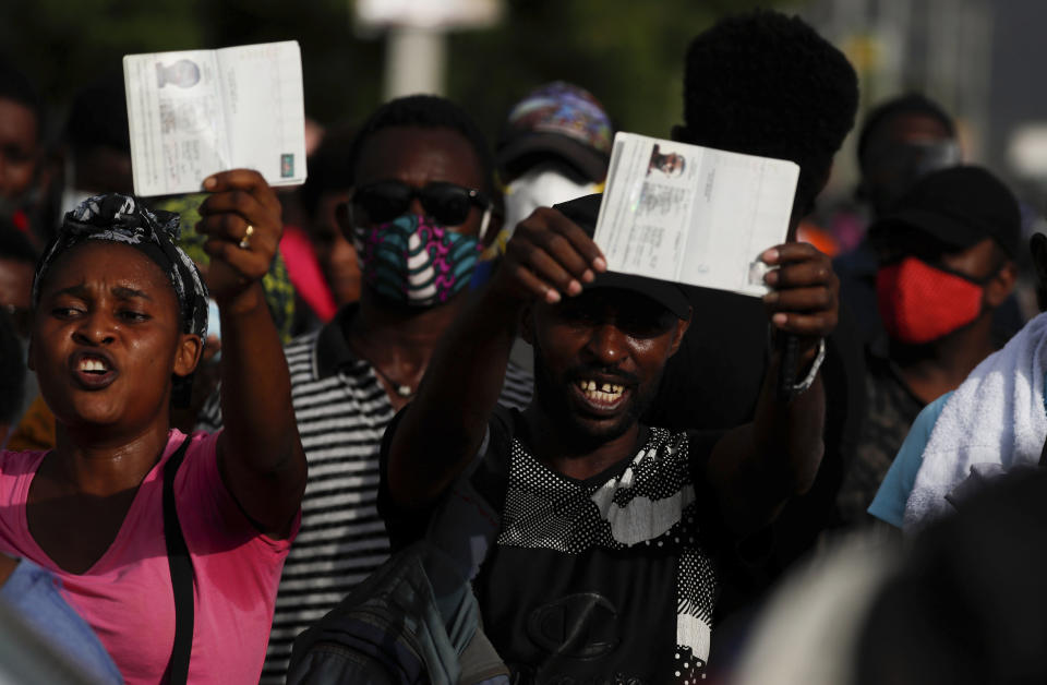 Haitians wave their passports shouting "Help, refugee," as they gather outside the U.S. Embassy in Port-au-Prince, Haiti, Friday, July 9, 2021. A large crowd gathered outside the embassy amid rumors on radio and social media that the U.S. will be handing out exile and humanitarian visas, two days after Haitian President Jovenel Moise was assassinated in his home. (AP Photo/Joseph Odelyn)