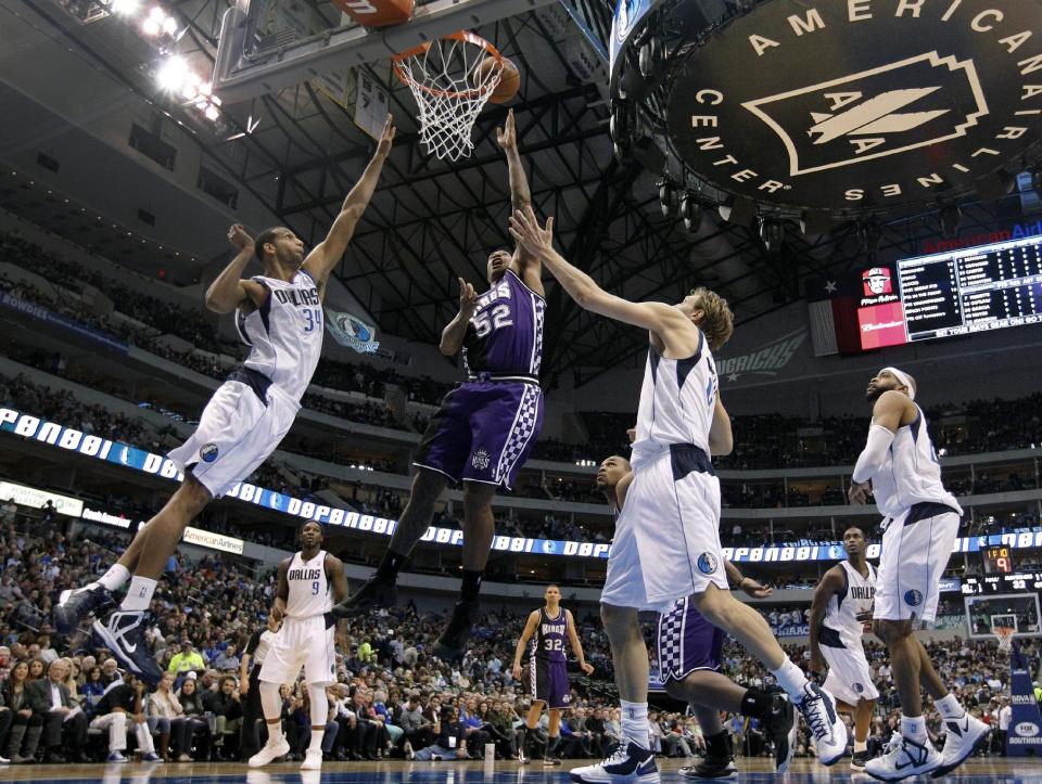 Dallas Mavericks' Brandan Wright, left, and Dirk Nowitzki, center right, of Germany defend as Sacramento Kings' James Johnson (52) goes up to score in the first half of an NBA basketball game Wednesday, Feb. 13, 2013, in Dallas. (AP Photo/Tony Gutierrez)