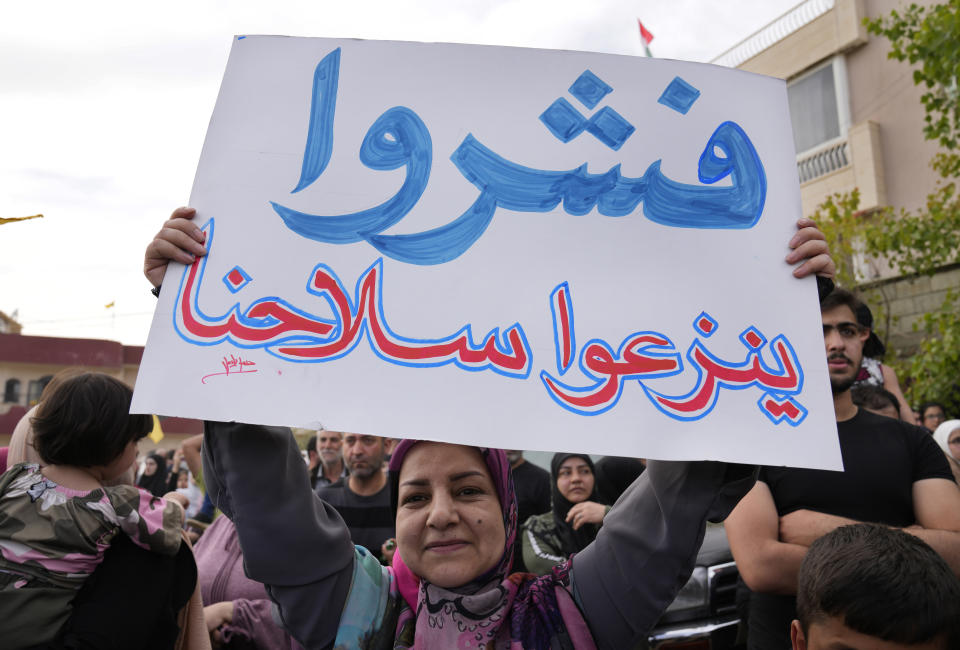 A Hezbollah supporter, holds up an Arabic banner that reads: On your dream to disarm us," during an election campaign, in Baalbek, east Lebanon, Friday, May 13, 2022. Despite a devastating economic collapse and multiple other crises gripping Lebanon, the culmination of decades of corruption and mismanagement, the deeply divisive issue of Hezbollah's weapons has been at the center of Sunday's vote for a new 128-member parliament. (AP Photo/Hussein Malla)