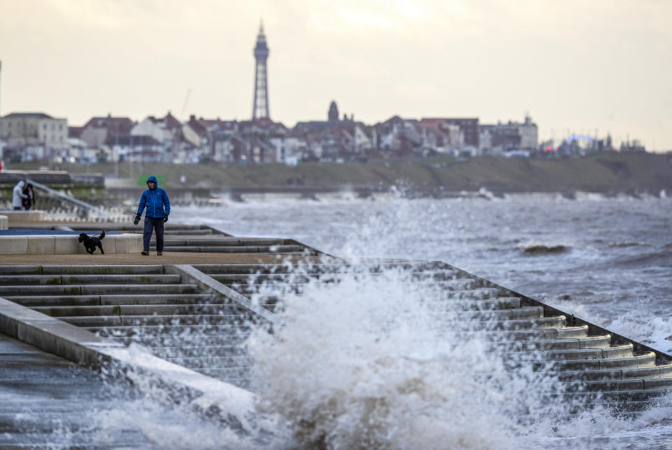 A man walks a dog along the promenade near Blackpool as gusts of up to 80mph could hit parts of the UK as Storm Brendan sweeps in. (Photo by Peter Byrne/PA Images via Getty Images)