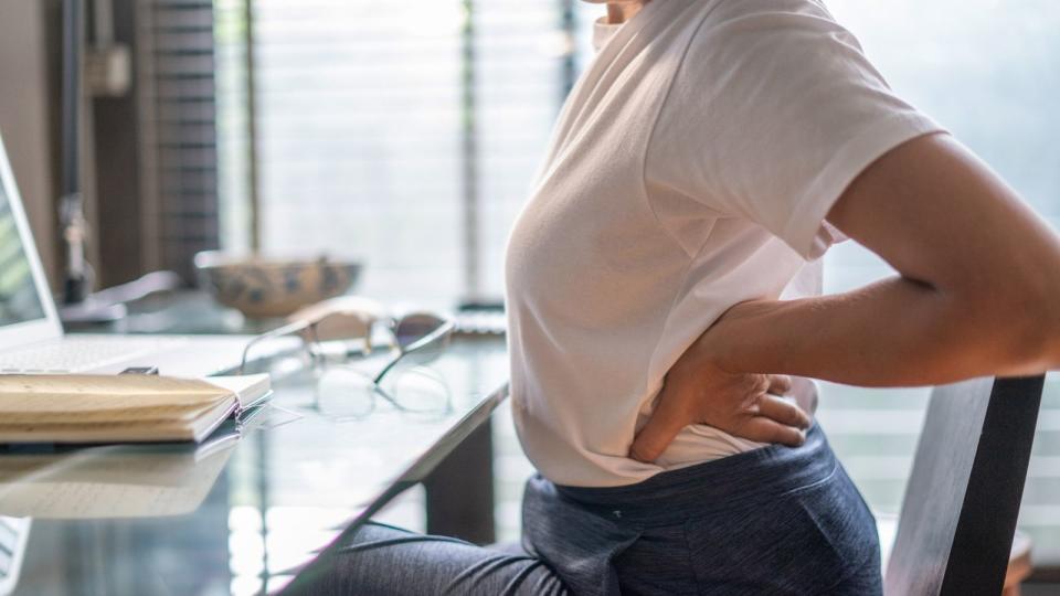 Woman stretching sore back working from home 