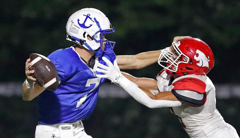 Scituate quarterback Jackson Belsan fights off a sack attempt by Milton captain Ben Caledonia during a football game in Scituate on Friday, Sept. 8, 2023.