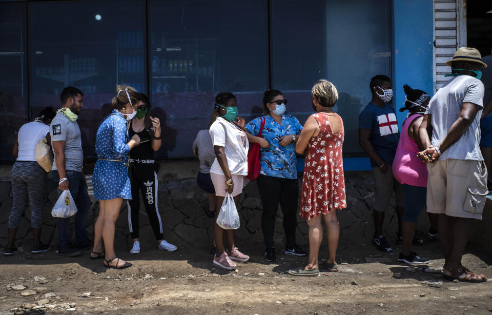 Afuera de una tienda estatal de comida, personas con mascarillas para protegerse del nuevo coronavirus esperan en línea para entrar en La Habana, Cuba, el martes 19 de mayo de 2020. (AP Foto/Ramon Espinosa)