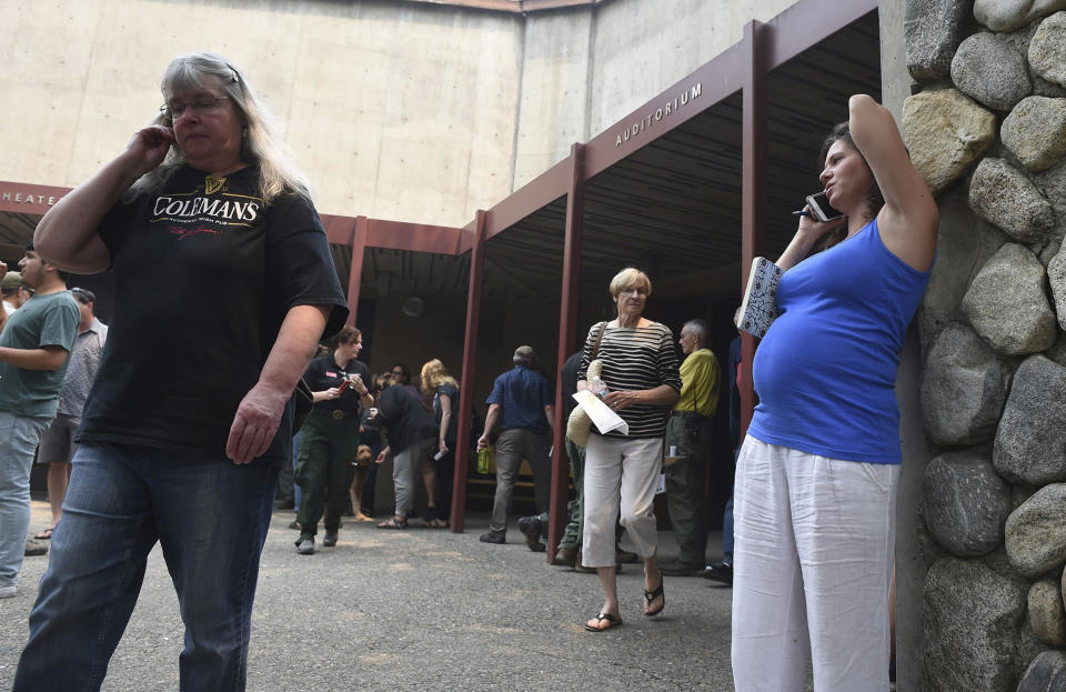 Brooke Smith, right, who lives in Yosemite Valley, talks on the phone after attending a community meeting for the latest information about the Ferguson Fire Tuesday, July 24, 2018, in Yosemite National Park, Calif. A Yosemite National Park official says at least a thousand campground and hotel reservations will be canceled after authorities decided to close Yosemite Valley to keep a growing forest fire at bay. Spokesman Scott Gediman says the valley, the heart of the visitor experience at the park, along with a windy, mountainous, 20-mile (32-kilometer) stretch of State Route 41 that is part of Yosemite will close beginning Wednesday at noon. (Eric Paul Zamora/The Fresno Bee via AP)