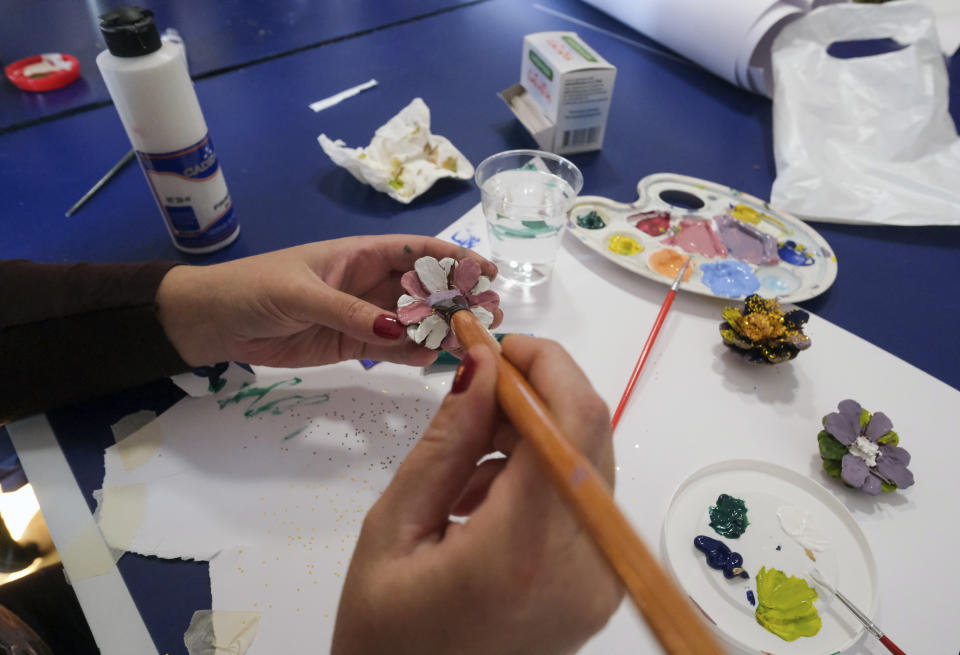 A a woman paints a pine cone during a therapy session in Sarajevo, Bosnia Monday, Oct. 26, 2020. As coronavirus cases surge in Bosnia, the pandemic is heaping new trouble on an impoverished nation that has never recovered economically or psychologically from a war in the 1990s. Bosnian health authorities estimate that nearly half of the Balkan nation’s nearly 3.5 million people have suffered some degree of trauma resulting from the war. (AP Photo/Kemal Softic)