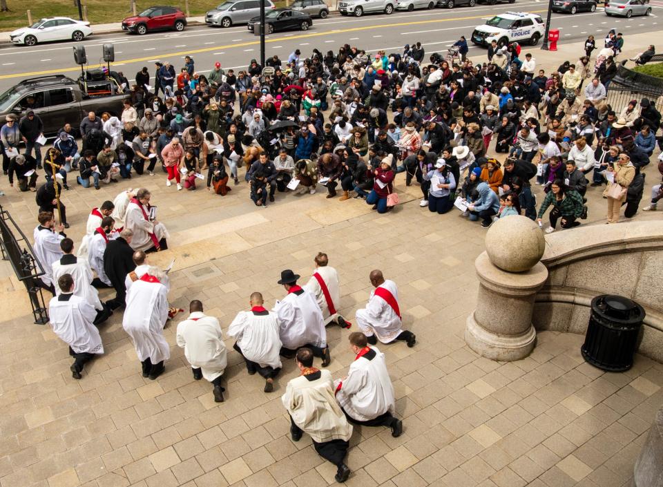 Christians kneel during a reciting of the Stations of the Cross in front of City Hall on Good Friday.