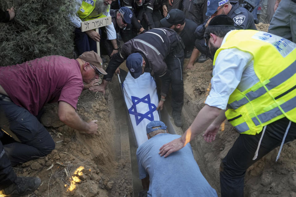 Mourners lower the body of Chen Amir into a grave, during his funeral in Kibbutz Re'im, Israel, Sunday, Aug 6, 2023. On Saturday a Palestinian gunman shot and killed Amir, 42, an Israeli security guard in central Tel Aviv. The attacker was shot and killed. (AP Photo/Tsafrir Abayov)