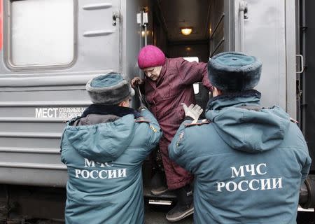 Russian Emergencies Ministry members help a woman out of a train, as refugees from eastern Ukraine arrive at a railway station in the southern city of Stavropol February 26, 2015. REUTERS/Eduard Korniyenko