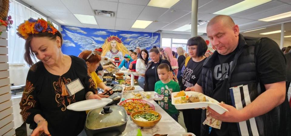 Line up of people getting homemade food made by Ukrainian newcomer volunteers at the opening of the Free Store community hub on May 4. 