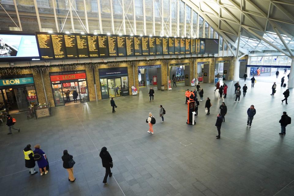 Passengers view departure boards at Kings Cross station in London (PA)