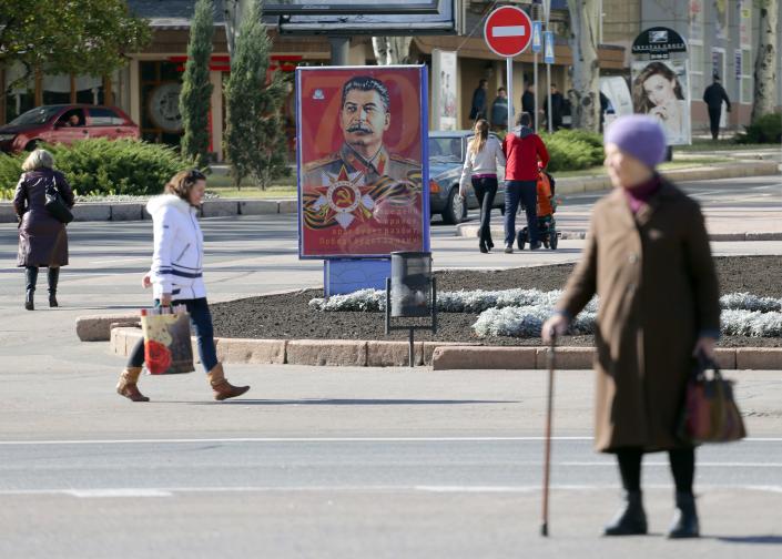 People walk past a portrait of Soviet dictator Josef Stalin on an advertising board, in Donetsk, on October 17, 2015. Three Stalin portraits hang in the centre of Donetsk, the main city held by pro-Russian rebels in eastern Ukraine, where a mood of nostalgia for the Soviet era is all-pervasive. (Aleksey Filippov/AFP via Getty Images)