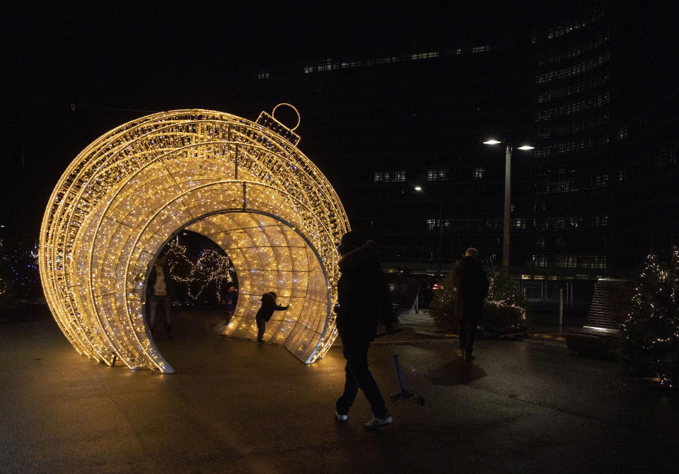 A young child plays inside of a giant Christmas ornament outside EU headquarters in Brussels, Wednesday, Dec. 23, 2020. Talks continued Wednesday in the bid to put a trade deal between the European Union and the United Kingdom, before a Brexit transition period ends on New Year's Day, with the EU legislature insisting it will not have time to approve a deal. (AP Photo/Virginia Mayo)