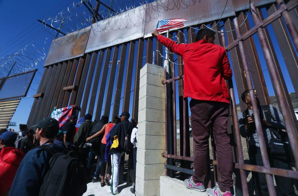 <p>Junior, a migrant from Honduras, waves the American flag while standing with other migrants at the U.S.-Mexico border fence on November 25, 2018 in Tijuana, Mexico.</p>